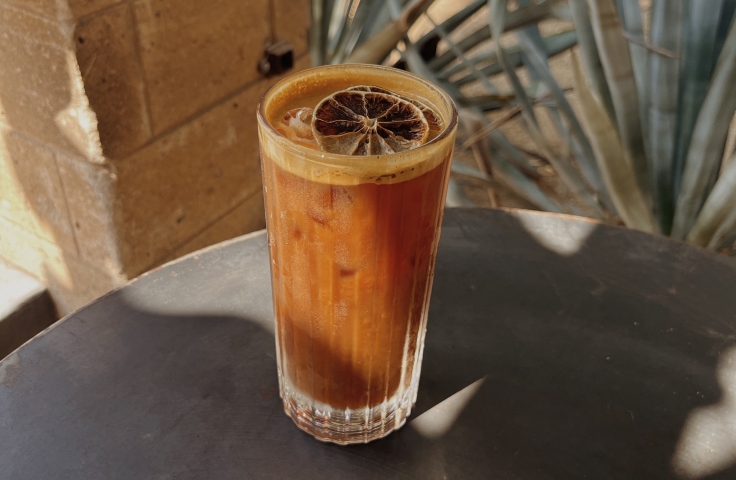 Cold drink with dried orange garnish at Cartel Coffee