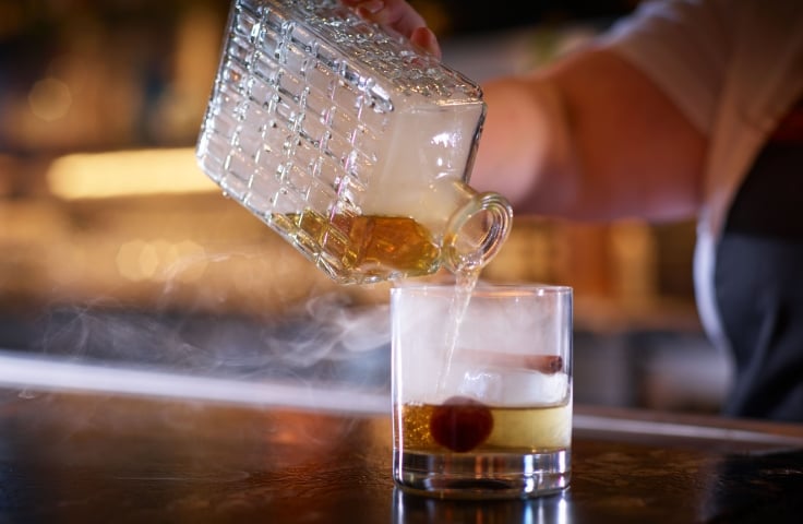 A server preparing a cocktail with a cherry, smokey whiskey at Yellowbell