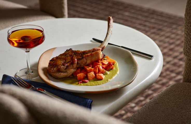 A cooked pork chop on carrots and a green sauce at Yellowbell