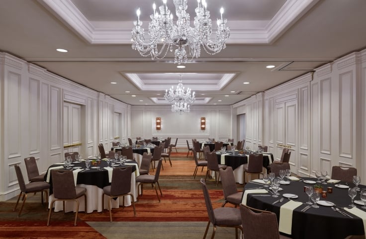 An indoor meeting space at the Camby with 6 large round tables setup for an event