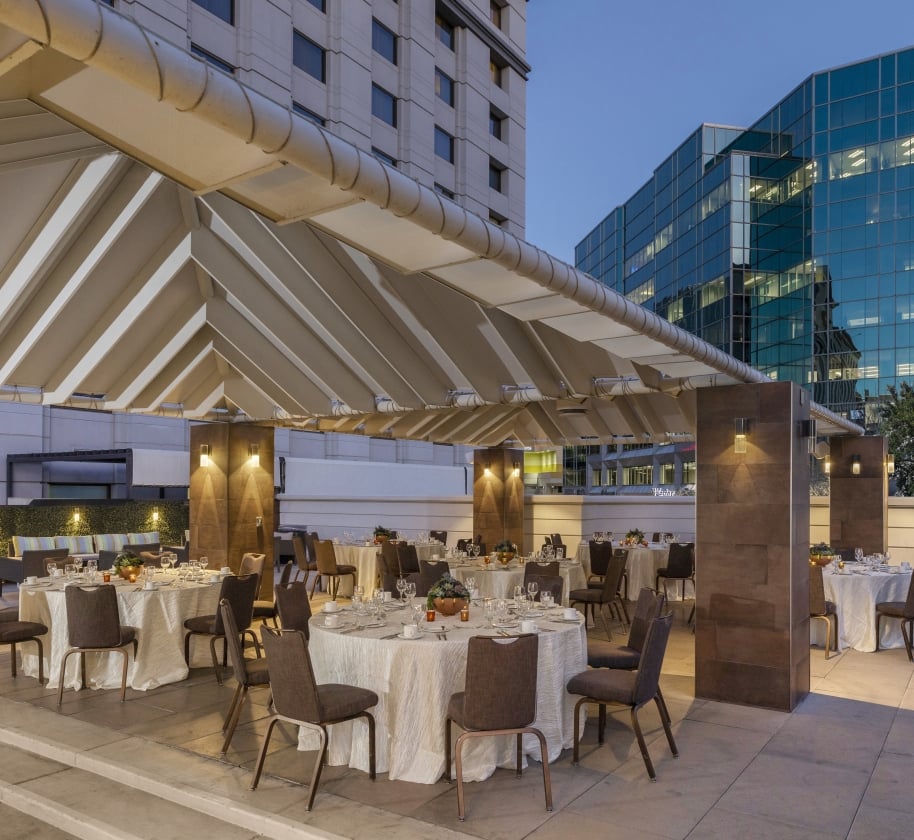 An outdoor gathering space at the Camby with several large round tables setup for an event