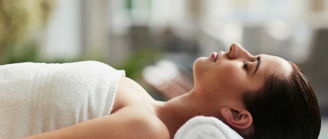 A woman laying on her back with. towel roll under her neck at Aji Spa