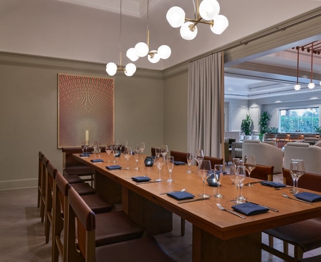 A private dining room with a long table set up for service at the Camby
