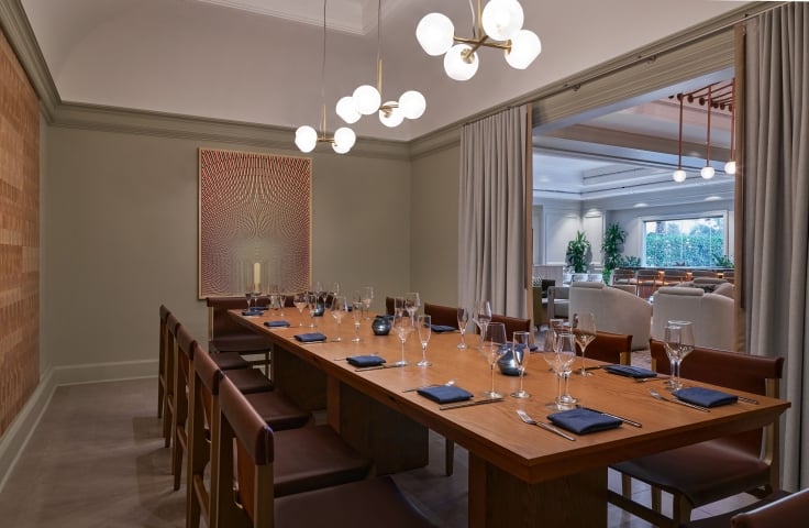 A private dining room with a long table set up for service at the Camby