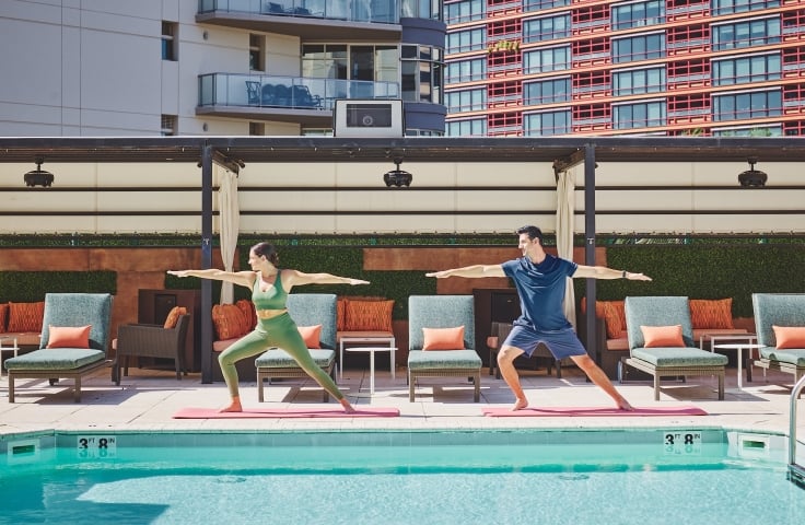 Two people doing yoga poolside