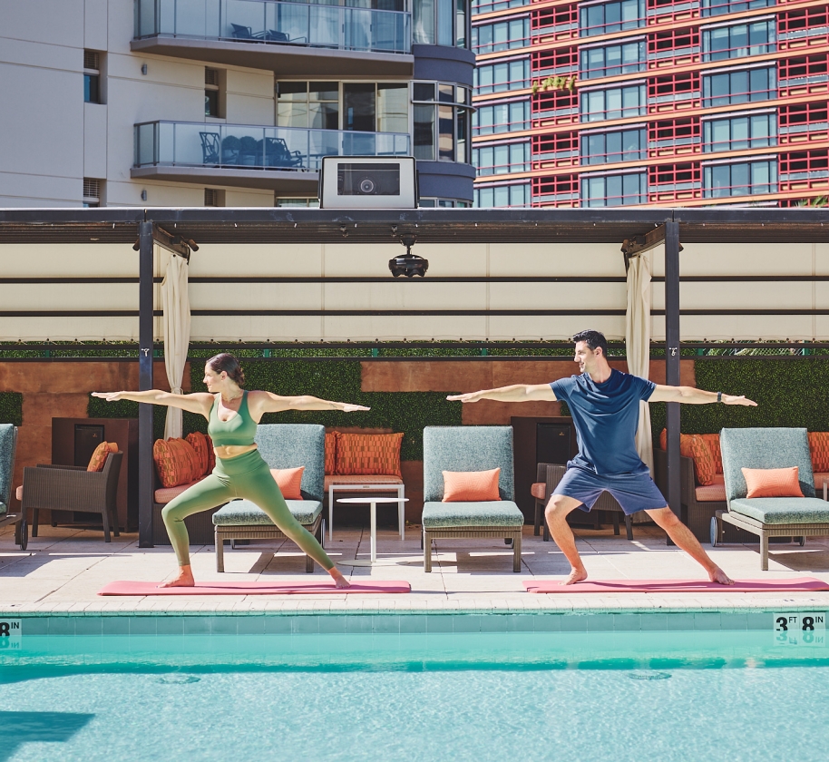 Two people doing yoga poolside