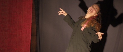 Older adult woman with dramatic gestures on theatrical stage.