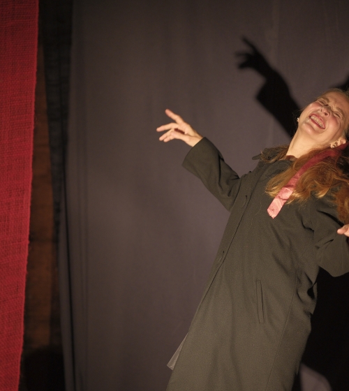 Older adult woman with dramatic gestures on theatrical stage.