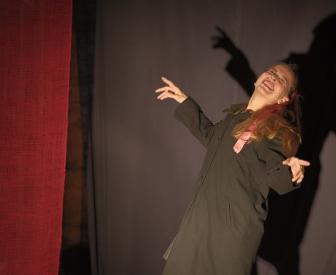 Older adult woman with dramatic gestures on theatrical stage.