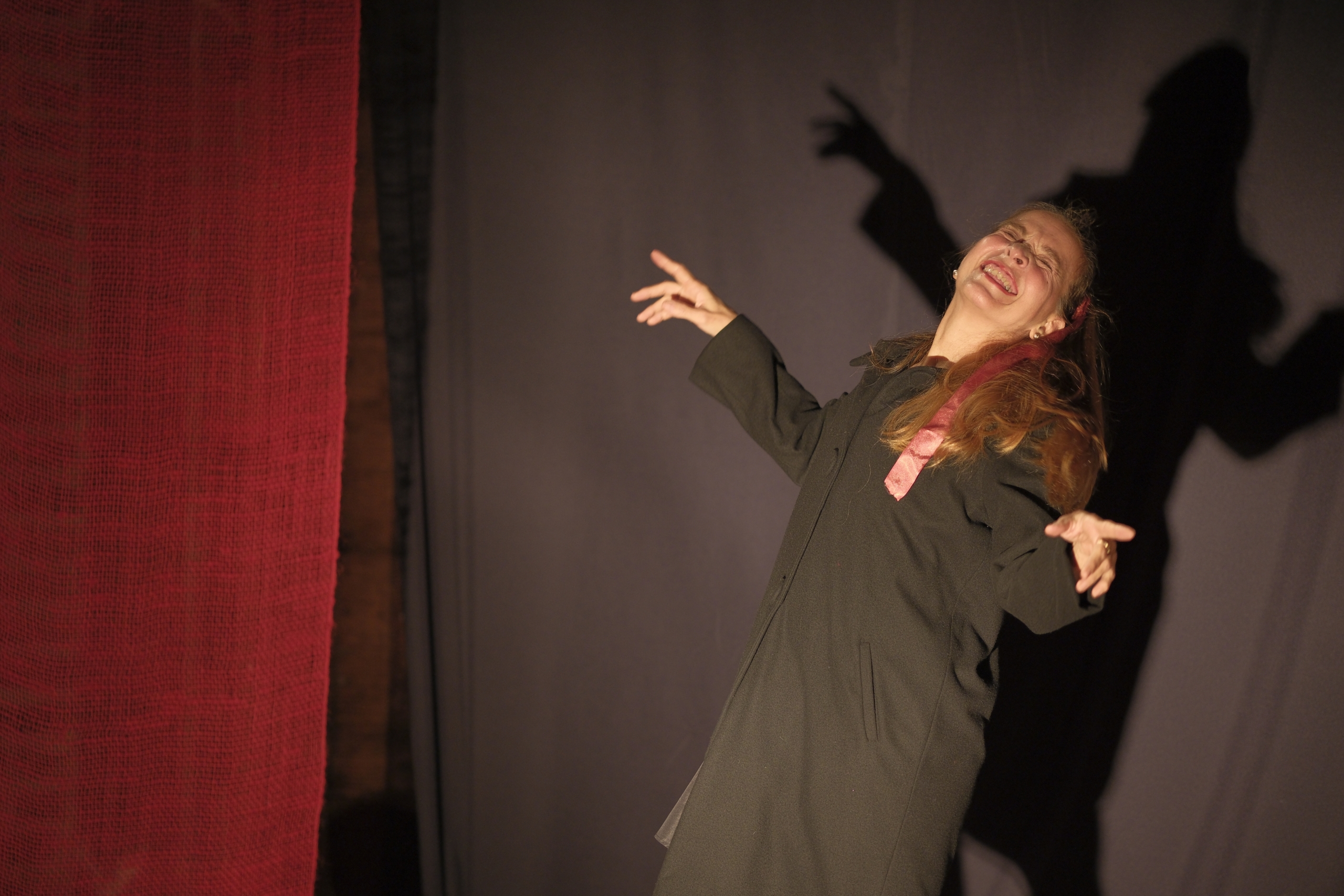 Older adult woman with dramatic gestures on theatrical stage.