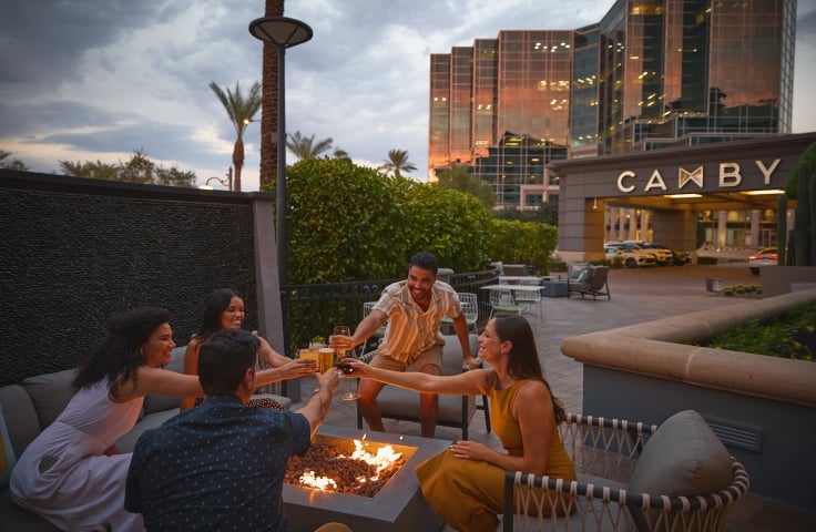 Men and women socializing over a firepit. Drinking, cheers, Yellowbell patio