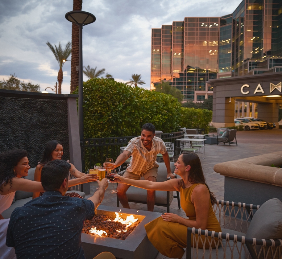 Men and women socializing over a firepit. Drinking, cheers, Yellowbell patio