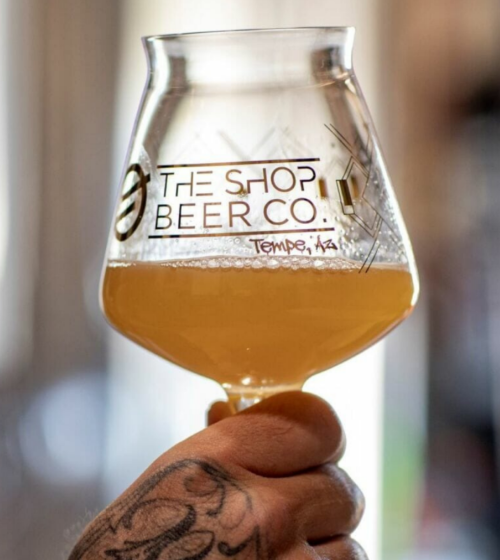 The Shop Beer Co. Beer glass and hand.