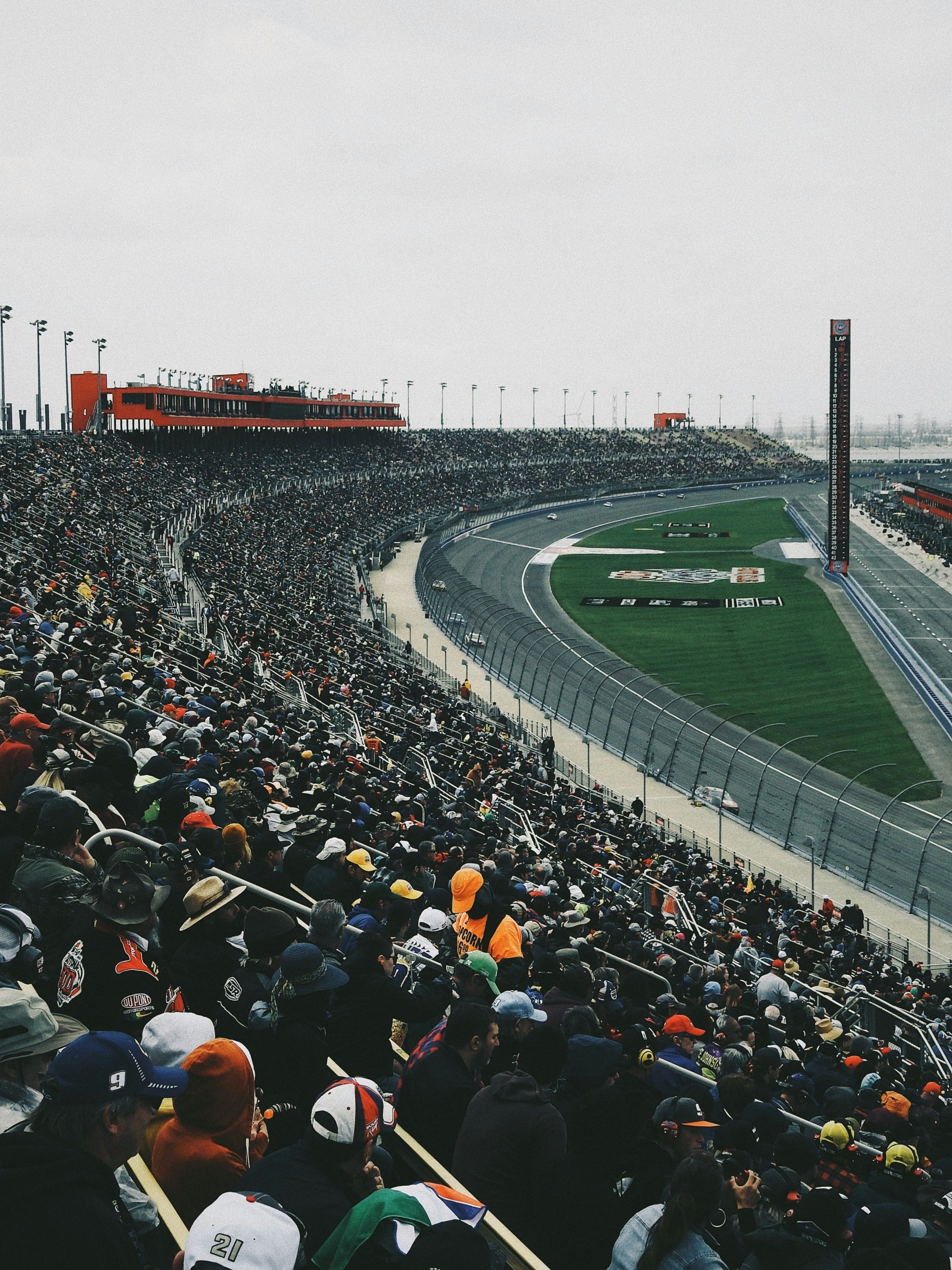 A crowd of people at a race track watching racecars.