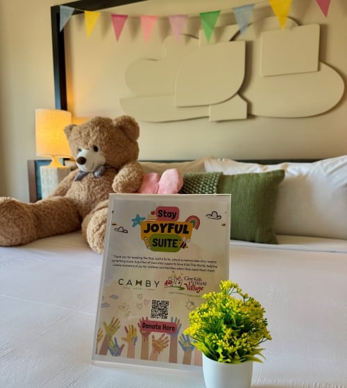 Bed with sign on it, flowers, teddy bear and pennants on headboard
