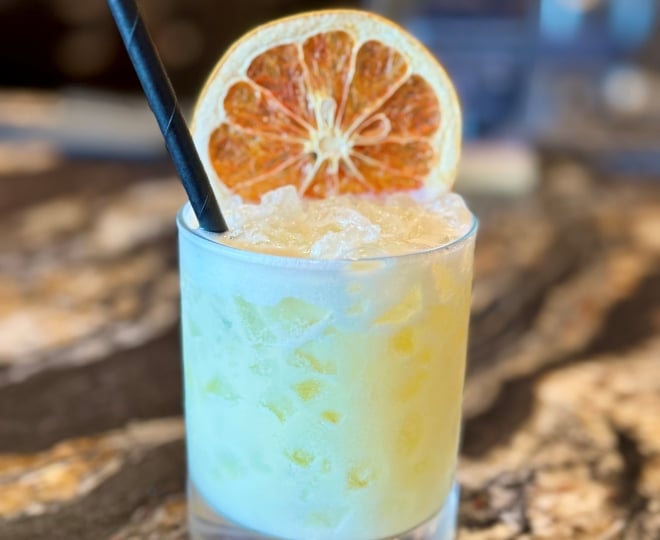 cocktail on a bar with a dehydrated orange wheel garnish