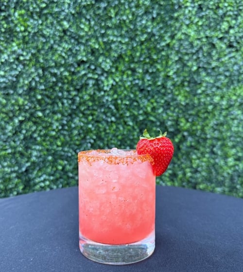 bright pinkish red cocktail with a strawberry garnish